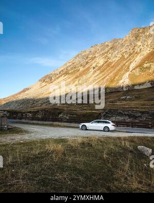 Weißer BMW-Wagen in den Lepontinischen Alpen. Seitenansicht des 5er BMW bei Sonnenuntergang. Stockfoto