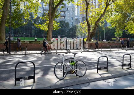 Geparkte Fahrrad- und Fahrradwege gegenüber den Menschen im Altab Ali Park am sonnigen Oktobertag auf der Whitechapel Road East End London England UK 2024 KATHY DEWITT Stockfoto