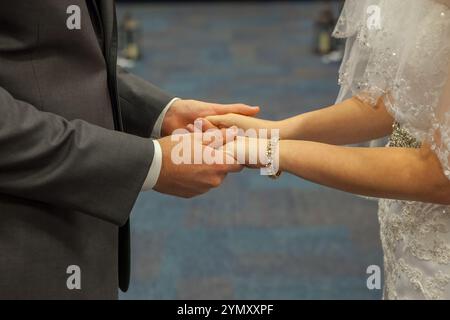 Braut und Bräutigam halten während der Hochzeitszeremonie Hände am Altar der Kirche Stockfoto