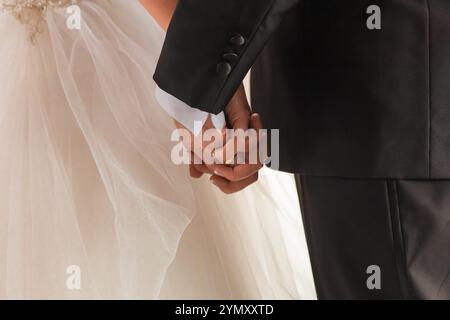 Romantischer Hochzeitstag: Braut und Bräutigam halten Hände in einem zeitlosen Moment Stockfoto