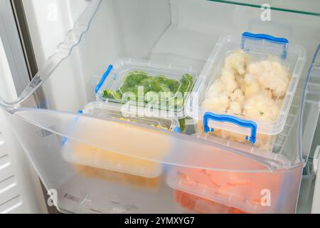 Kunststoffbehälter mit verschiedenen Tiefkühlgemüse im Kühlschrank Stockfoto