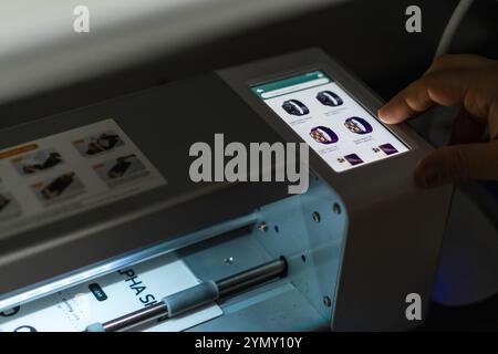 Der Benutzer arbeitet tagsüber mit einem präzisen Plotter zum Schneiden von Hydrogelfolie in einem modernen Arbeitsbereich zusammen Stockfoto