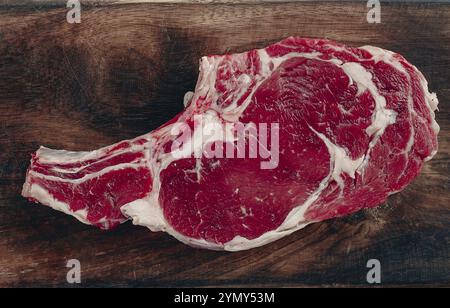 Rohes Rib Eye Steak, Cowboy Steak, hölzerne Schneidebrett, Marmortisch, Draufsicht, keine Personen Stockfoto