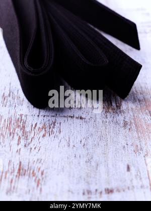 Schwarzer Karategürtel auf rustikalem Holzhintergrund. Stockfoto
