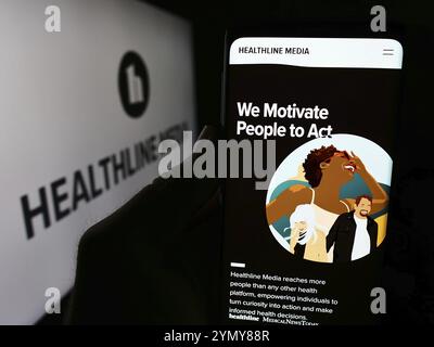 Stuttgart, Deutschland, 06-03-2024: Person, die ein Mobiltelefon hält, mit Webseite des US-Gesundheitsinformationsunternehmens Healthline Media LLC vor dem Logo. Konzentrieren Sie sich auf Stockfoto