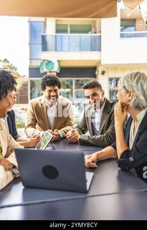 Vertikales Foto einer Gruppe verschiedener Geschäftsleute, die während eines Meetings in einer Cafeteria mit Laptop arbeiten Stockfoto