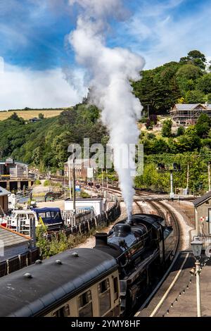 Eine alte Dampfeisenbahn mit wehendem Rauch, die an einem sonnigen Tag in die Station Dartmouth mit malerischer Aussicht kommt Stockfoto