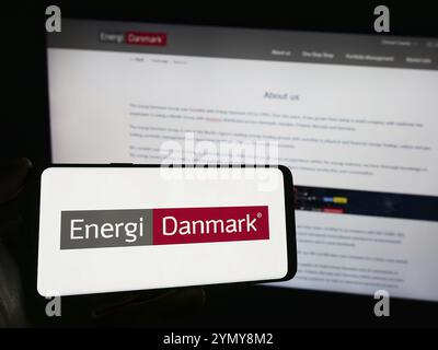 Stuttgart, Deutschland, 03.01.2024: Person, die ein Mobiltelefon mit dem Logo des dänischen Energiehandelsunternehmens Energi Danmark WIE vor der Webseite hält Stockfoto