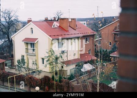 Umgeben von Backsteinhäusern, fällt ein weißes Haus mit einem roten Dach aus, 35 mm Folie Stockfoto