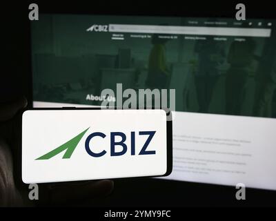 Stuttgart, Deutschland, 07.06.2024: Person, die ein Mobiltelefon mit dem Logo der amerikanischen Finanzberatungsgesellschaft CBIZ Inc. Vor der Business-Webseite hält Stockfoto