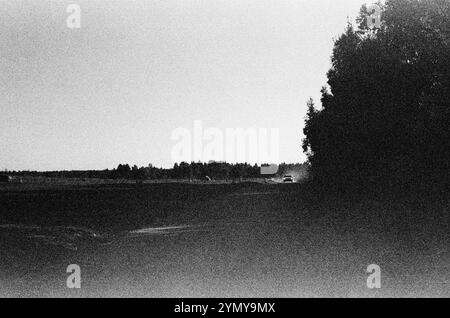 Ein Graustufenbild zeigt eine Landschaft mit Bäumen im fernen Hintergrund unter einem Himmel, Film 35 mm Stockfoto