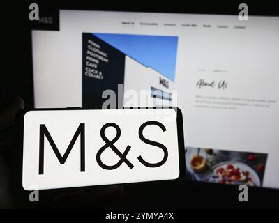 Stuttgart, Deutschland, 18.03.2024: Person mit Smartphone mit Logo des britischen Einzelhandelsunternehmens Marks and Spencer Group plc vor der Website. Fokus o Stockfoto