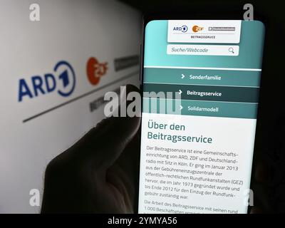 Stuttgart, 10.04.2024: Handybesitzer mit Website des ARD ZDF Deutschlandradio Beitragsservice vor Logo. Konzentrieren Sie sich auf die Mitte von Stockfoto