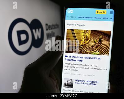 Stuttgart, 10.04.2024: Handybesitzer mit Internetseite der Deutschen Welle (DW) vor Logo. Konzentrieren Sie sich auf Stockfoto