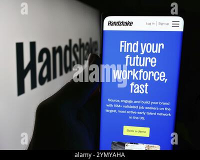 Stuttgart, Deutschland, 06-03-2024: Person, die ein Mobiltelefon mit Webseite des US-amerikanischen Recruiting-Software-Unternehmens Stryder Corp. (Handshake) mit Logo hält. Konzentrieren Sie sich auf Stockfoto