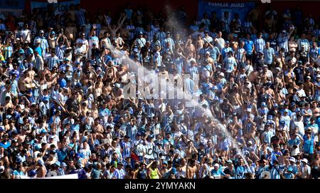 Die Fans des argentinischen Racing Clubs werden mit Wasser besprüht, während sie auf den Start des Finalspiels der CONMEBOL Copa Sudamericana gegen den brasilianischen Cruzeiro im La Nueva Olla Stadion in Asuncion, Paraguay, am 23. November 2024 warten. Stockfoto