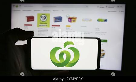 Stuttgart, 21.07.2024: Person mit Handy mit Logo des australischen Einzelhandelskettenunternehmens Woolworths Supermarkets vor der Webseite. Foc Stockfoto