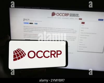 Stuttgart, 22.05.2024: Person, die ein Smartphone mit dem Logo des Organized Crime and Corruption Reporting Project (OCCRP) vor der Website hält. F Stockfoto