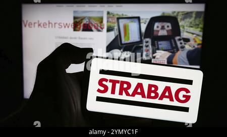 Stuttgart, Deutschland, 15.04.2024: Handybesitzer mit Logo des österreichischen Bauunternehmens Strabag SE vor der Business-Webseite. Konzentrieren Sie sich auf Stockfoto