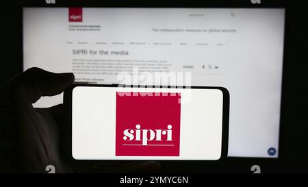 Stuttgart, 23.05.2024: Person mit Handy mit Logo des Stockholm International Peace Research Institute (SIPRI) vor der Webseite. Fo Stockfoto