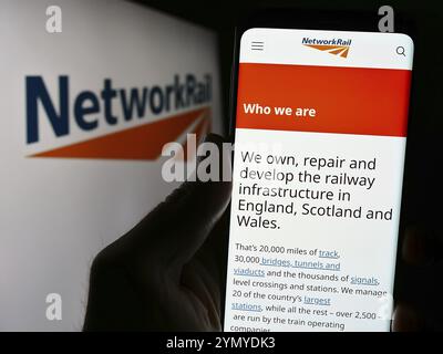 Stuttgart, Deutschland, 27.03.2024: Person, die ein Mobiltelefon hält, mit der Webseite des Eisenbahninfrastrukturunternehmens Network Rail Limited vor dem Logo. Fokus o Stockfoto