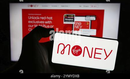 Stuttgart, Deutschland, 18.03.2024: Person, die ein Mobiltelefon mit dem Logo des britischen Finanzdienstleisters Virgin Money vor der Business-Webseite hält Stockfoto