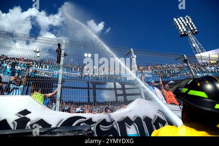 Die Fans des argentinischen Racing Clubs werden mit Wasser besprüht, während sie auf den Start des Finalspiels der CONMEBOL Copa Sudamericana gegen den brasilianischen Cruzeiro im La Nueva Olla Stadion in Asuncion, Paraguay, am 23. November 2024 warten. Stockfoto