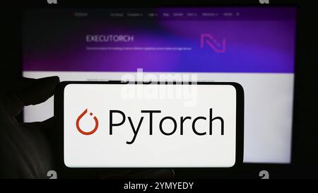 Stuttgart, Deutschland, 03.12.2024: Person mit Handy mit Logo der Bibliothek für maschinelles Lernen PyTorch vor der Webseite. Schwerpunkt auf Telefondisplay, EU Stockfoto