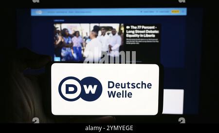 Stuttgart, 10.04.2024: Person mit Handy mit Logo der Deutschen Welle (DW) vor der Webseite. Konzentrieren Sie sich auf Stockfoto