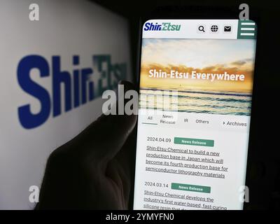 Stuttgart, Deutschland, 13.04.2024: Person, die ein Smartphone mit Webseite des japanischen Chemieunternehmens Shin-Etsu Chemical Co. Ltd. Mit Logo hält. Konzentrieren Sie sich auf c Stockfoto