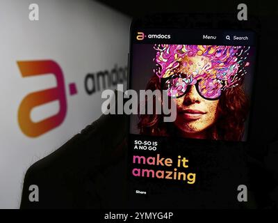Stuttgart, Deutschland, 27.05.2024: Person, die ein Mobiltelefon hält, mit Website des israelischen Telekommunikationsunternehmens Amdocs Limited vor dem Logo. Konzentrieren Sie sich auf Stockfoto
