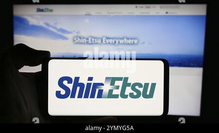 Stuttgart, Deutschland, 13.04.2024: Person mit Mobiltelefon mit Logo des japanischen Chemieunternehmens Shin-Etsu Chemical Co. Ltd. Vor der Webseite. Stockfoto