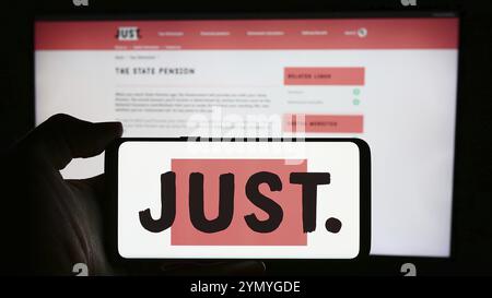 Stuttgart, Deutschland, 23.03.2024: Person mit Mobiltelefon mit Logo des britischen Finanzdienstleistungsunternehmens Just Group plc vor der Business-Website. Stockfoto