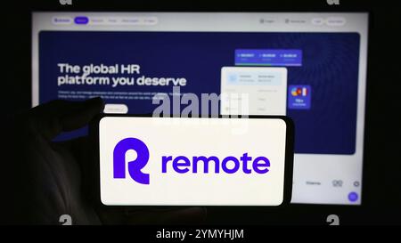 Stuttgart, Deutschland, 13.06.2024: Person, die ein Mobiltelefon mit dem Logo des US-amerikanischen HR-Softwareunternehmens Remote Technology Inc. Vor der Website des Unternehmens hält. Fokussieren Stockfoto