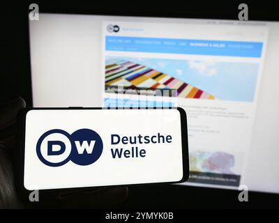 Stuttgart, Deutschland, 10.04.2024: Person mit Smartphone mit Logo der Deutschen Welle (DW) vor der Website. Fokus o Stockfoto