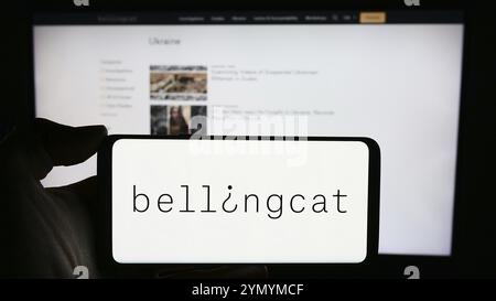 Stuttgart, Deutschland, 03.06.2024: Person mit Handy mit Logo der niederländischen investigativen Journalismusorganisation Bellingcat vor der Webseite. Fokussieren Stockfoto