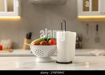 Papierrolle und Gemüse auf weißem Marmortisch in der Küche Stockfoto