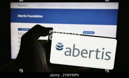 Stuttgart, Deutschland, 13.04.2024: Person mit Mobiltelefon mit Logo des spanischen Mautunternehmens Abertis Infraestructuras SA vor der Website. Fo Stockfoto