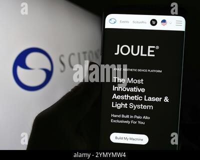 Stuttgart, Deutschland, 04.05.2024: Person, die ein Smartphone hält, mit Webseite des US-amerikanischen Medizinprodukteunternehmens Sciton Inc. Vor dem Geschäftslogo. Fokus auf ce Stockfoto