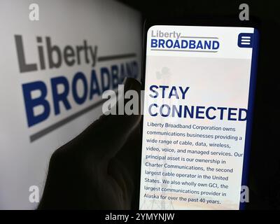 Stuttgart, 26.06.2024: Person, die ein Mobiltelefon hält, mit Webseite der US-amerikanischen Liberty Broadband Corporation (LBRDA) vor dem Logo. Konzentrieren Sie sich auf c Stockfoto