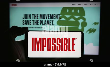 Stuttgart, 21.05.2024: Person, die ein Mobiltelefon mit dem Logo des US-amerikanischen Fleischersatzunternehmens Impossible Foods Inc. Vor der Webseite hält. F Stockfoto