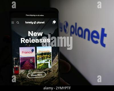 Stuttgart, Deutschland, 06.03.2024: Person, die ein Mobiltelefon hält, mit Webseite der Reiseleitung Lonely Planet vor dem Firmenlogo. Konzentrieren Sie sich auf Stockfoto