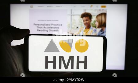Stuttgart, Deutschland, 22.05.2024: Person, die ein Mobiltelefon mit dem Logo der Houghton Mifflin Harcourt Publishing Company (HMH) vor der Webseite hält. Stockfoto