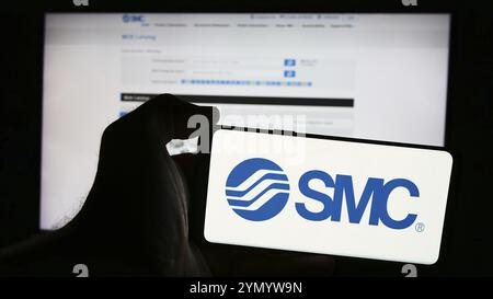 Stuttgart, Deutschland, 25.07.2024: Person, die ein Mobiltelefon mit dem Logo des japanischen Maschinenunternehmens SMC Corporation vor der Business-Webseite hält. Foc Stockfoto