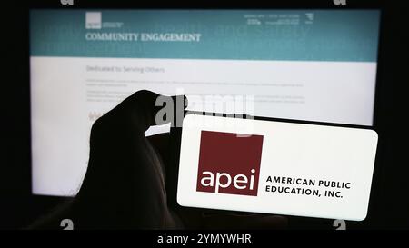 Stuttgart, Deutschland, 07.08.2024: Person mit Smartphone mit Logo des US-amerikanischen Unternehmens American Public Education Inc. (APEI) vor der Website. Konzentrieren Sie sich auf Stockfoto