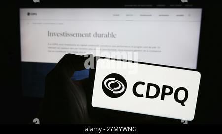 Stuttgart, Deutschland, 03.06.2024: Person, die ein Mobiltelefon mit dem Logo der Caisse de Depot et Placement du Quebec (CDPQ) vor der Webseite für Unternehmen hält. Stockfoto