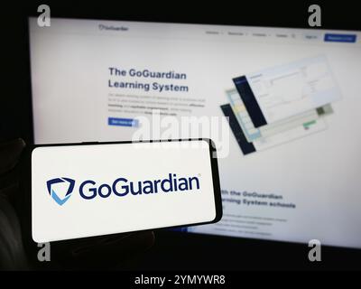 Stuttgart, Deutschland, 03.05.2024: Person, die ein Mobiltelefon mit dem Logo des US-amerikanischen Bildungssoftware-Unternehmens Liminex Inc. (GoGuardian) vor der Web-pag hält Stockfoto