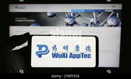 Stuttgart, Deutschland, 03.05.2024: Person mit Handy mit Logo des chinesischen Pharmaunternehmens Wuxi AppTec Co. Ltd. Vor der Webseite Stockfoto