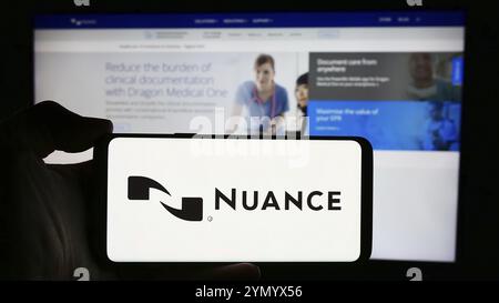Stuttgart, Deutschland, 04.10.2024: Person, die ein Mobiltelefon mit dem Logo des US-Softwareunternehmens Nuance Communications Inc. Vor der Webseite hält. Foc Stockfoto