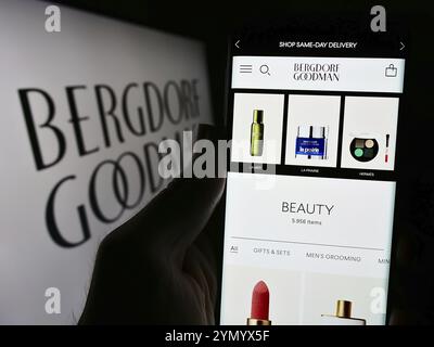 Stuttgart, Deutschland, 26.02.2024: Person, die ein Mobiltelefon mit Webseite des US-amerikanischen Kaufhausunternehmens Bergdorf Goodman Inc. Mit Logo hält. Konzentrieren Sie sich auf Stockfoto